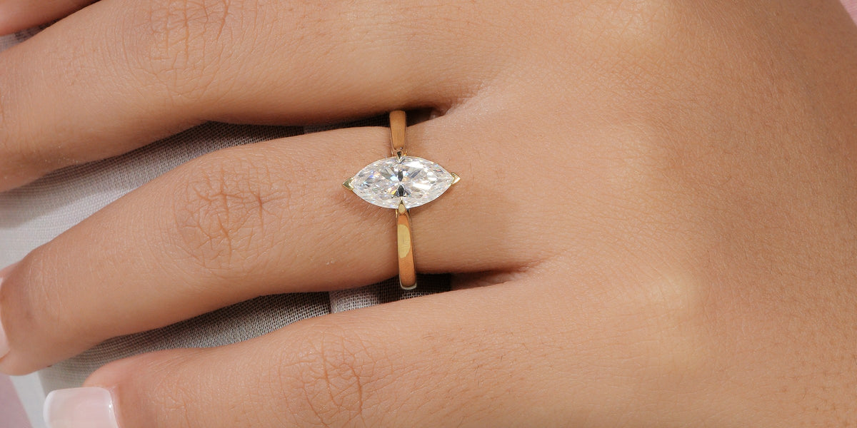 Marquise-cut lab-grown diamond solitaire engagement ring in yellow gold, worn on a hand