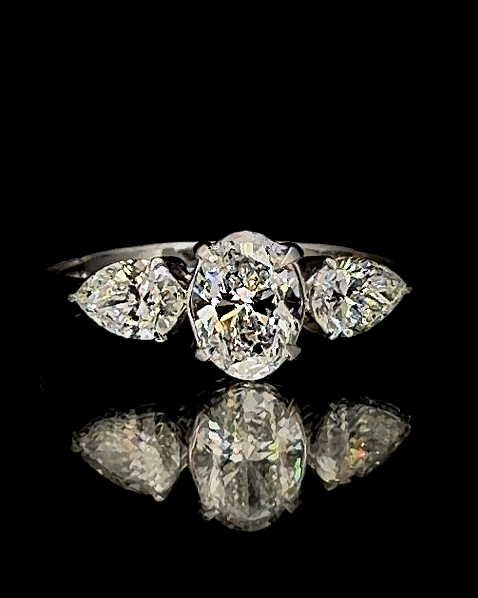 Main: White gold 7.09ct oval three-stone ring with pear-cut lab grown diamond sides on black
Detail: Close-up of oval lab grown diamond centre flanked by two pear-cut diamonds in white gold
Side: White gold three-stone ring with raised oval centre and pear-shaped lab grown diamond sides