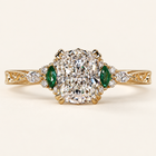 Cushion cut lab grown diamond engagement ring with green marquise emerald gemstones, round diamond accents, decorative filigree and milgrain yellow gold shoulders.