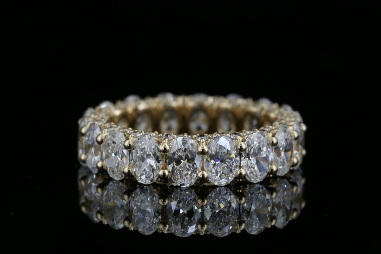 Yellow gold eternity ring with 5.280ct oval lab grown diamonds photographed on black