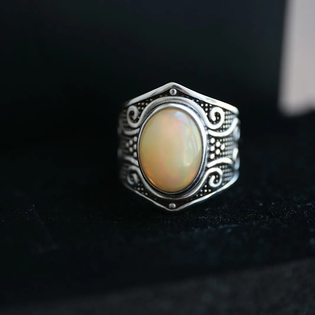 Ornate silver ring with an oval gemstone in a velvet box