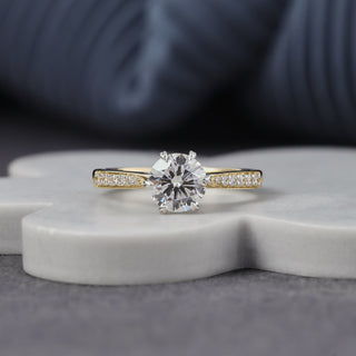 Round cut lab grown diamond engagement ring with 1.00 ct center, six-prong basket, pavé-set shoulders and hidden diamond accents in yellow gold with white-tone prongs.