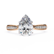 Rose gold ring with a large pear-shaped diamond and smaller diamonds on the band against a white background