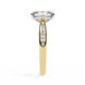 Gold ring with a large diamond and smaller diamonds on the band against a white background
