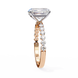 Rose gold ring with a large diamond and smaller diamonds on the band against a white background