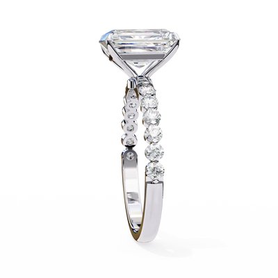 Diamond ring with a large central stone and smaller stones on the band against a white background