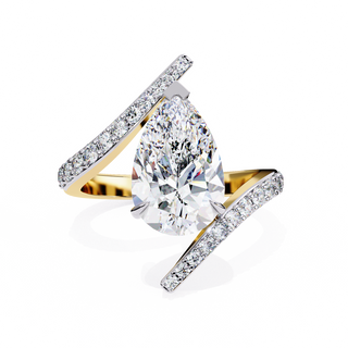 Front-facing view of a yellow gold pear diamond bypass pavé ring.