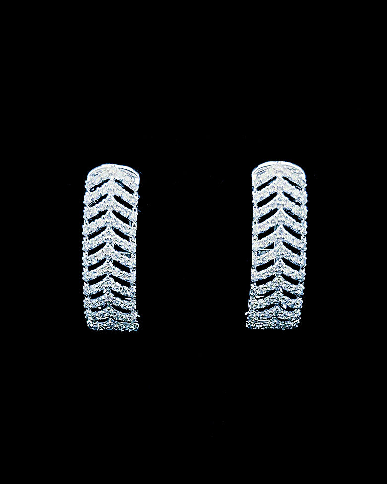 White gold chevron pavé huggie earrings with round lab-grown diamonds on a black background