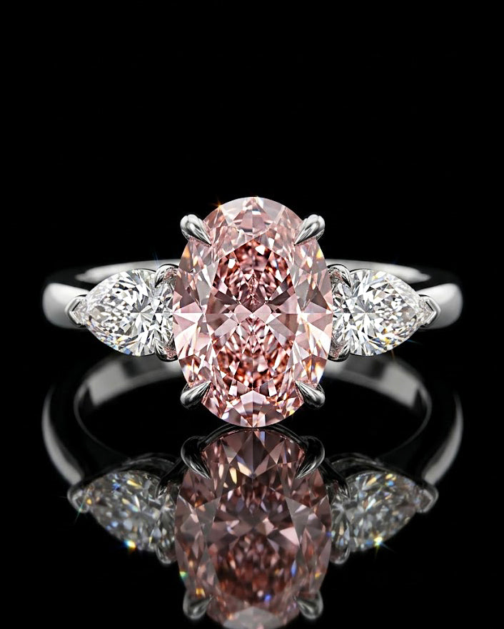 Main: White gold 7.09ct oval three-stone ring with pear-cut lab grown diamond sides on black
Detail: Close-up of large oval lab grown diamond flanked by two pear-cut diamonds in white gold
Side: White gold three-stone ring showing raised oval centre and pear-cut lab grown diamond side settings