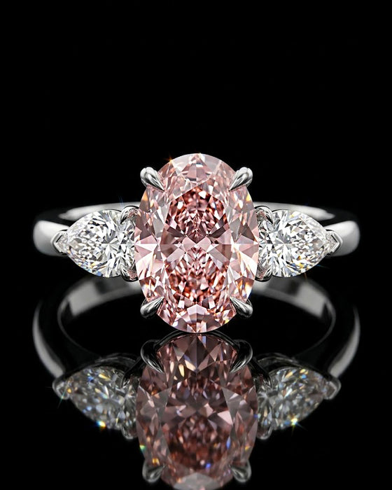 Main: White gold 7.09ct oval three-stone ring with pear-cut lab grown diamond sides on black
Detail: Close-up of large oval lab grown diamond flanked by two pear-cut diamonds in white gold
Side: White gold three-stone ring showing raised oval centre and pear-cut lab grown diamond side settings