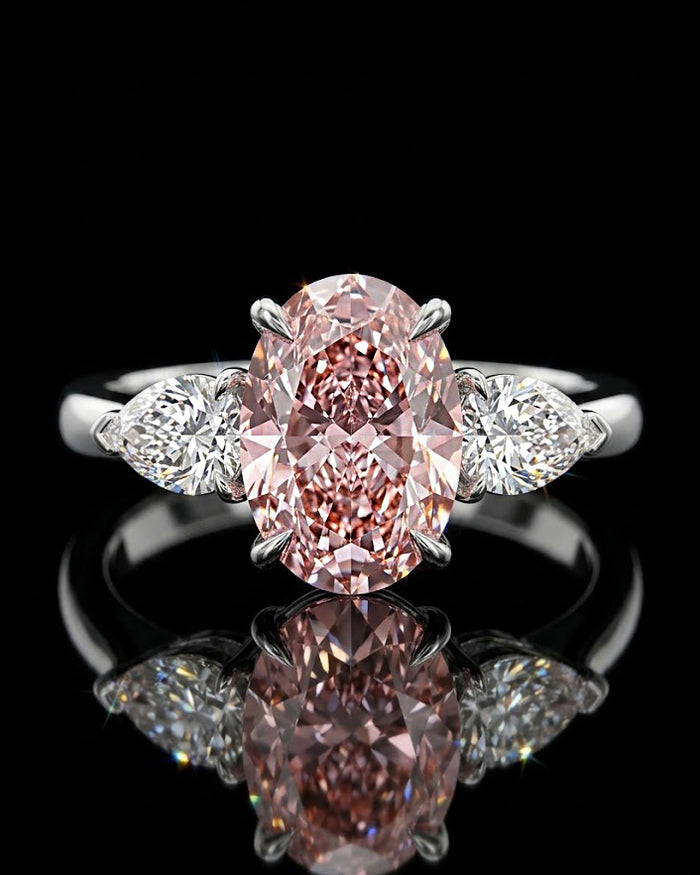 Main: White gold 7.09ct oval three-stone ring with pear-cut lab grown diamond sides on black
Detail: Close-up of large oval lab grown diamond flanked by two pear-cut diamonds in white gold
Side: White gold three-stone ring showing raised oval centre and pear-cut lab grown diamond side settings