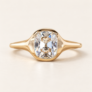 Cushion old mine cut lab grown diamond bezel engagement ring in yellow gold with broad tapered shoulders and polished shank