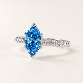 Fancy blue marquise cut lab grown diamond engagement ring with protective six-prong center setting and round diamond pavé shoulders in polished white gold.