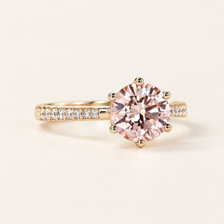 Fancy pink round cut lab grown diamond engagement ring with eight-prong yellow gold basket, white diamond pavé shoulders and polished gold shank.
