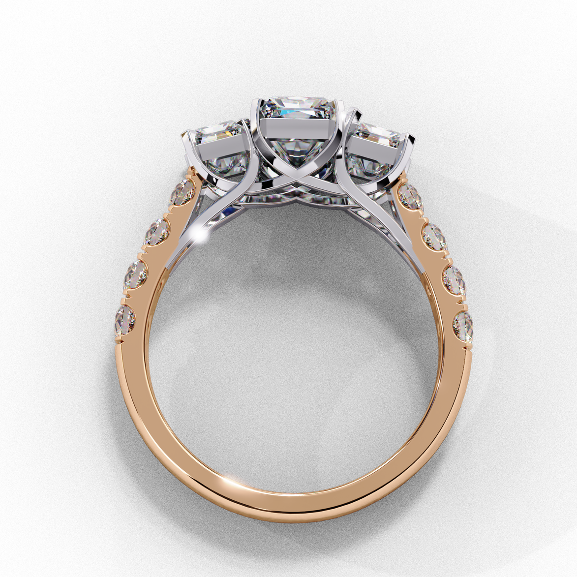 Side profile view of a rose gold radiant cut three-stone diamond engagement ring with an open basket setting.