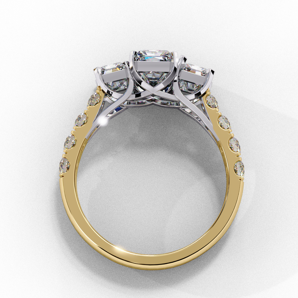 Side profile view of a yellow gold radiant cut three-stone diamond engagement ring with an open basket setting.