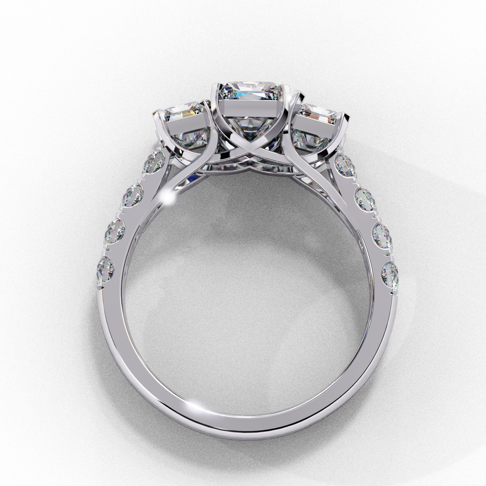 Side profile view of a white gold radiant cut three-stone diamond engagement ring with an open basket setting.