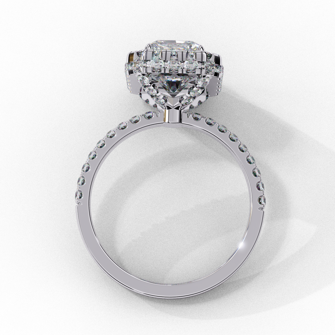 Side profile view of a white gold emerald cut diamond double halo engagement ring showing the elevated cathedral gallery.