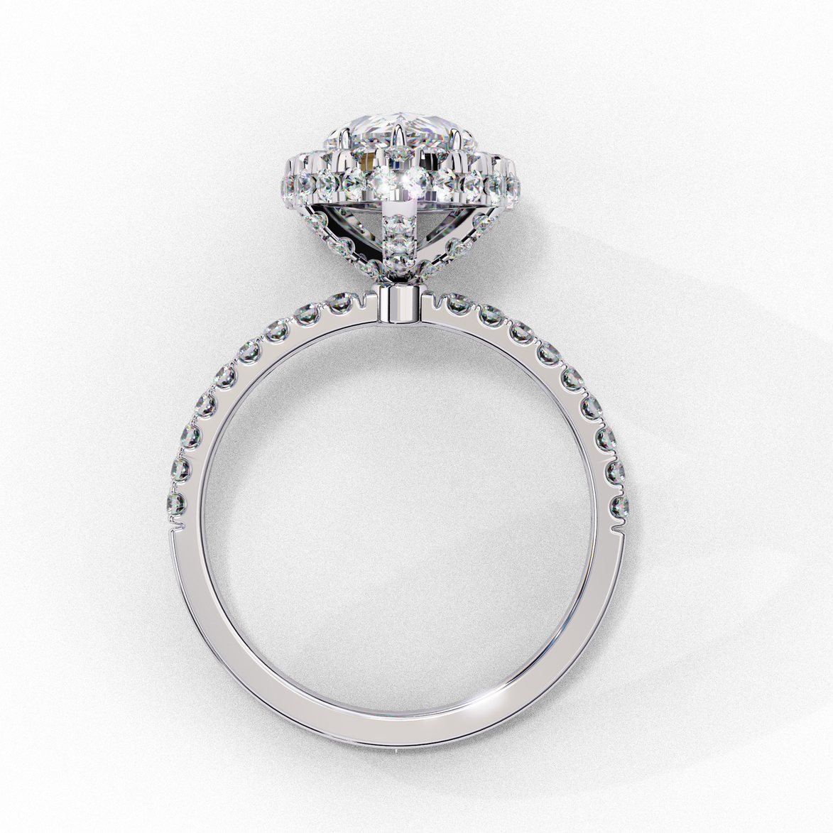 Side profile view of a white gold pear shaped diamond halo engagement ring showing the elevated cathedral gallery.