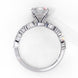 Side profile view of a white gold emerald cut diamond engagement ring showcasing the classic four-prong head structure.
