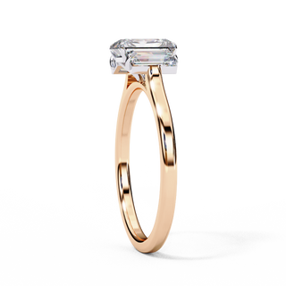 Side profile view of a rose gold emerald cut three stone diamond engagement ring.