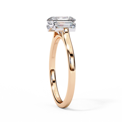 Side profile view of a rose gold emerald cut three stone diamond engagement ring.