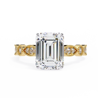 Gold ring with a large emerald-cut diamond and smaller diamonds on the band against a white background