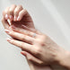 Close-up of a hand wearing a diamond ring on a light background