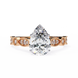 Rose gold ring with a pear-shaped diamond on a white background