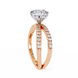 Rose gold ring with a large diamond and smaller diamonds on the band against a white background