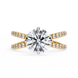 Gold ring with a large diamond and smaller diamonds on the band against a white background