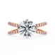 Gold ring with a large diamond and smaller diamonds on the band against a white background