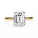 Gold ring with a large emerald-cut diamond on a white background