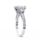 Diamond ring with a large central gemstone and smaller stones on the band against a white background