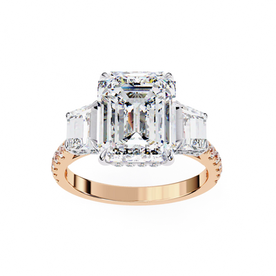 Rose gold ring with a large diamond and emerald-cut side stones on a white background