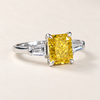 Vivid yellow radiant cut lab grown diamond three stone engagement ring in white gold with four-prong center and tapered baguette accents