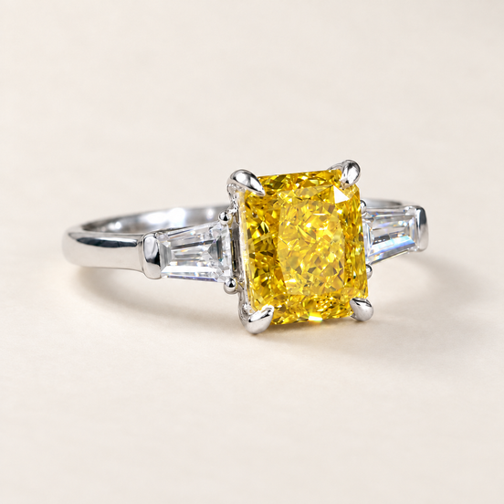 Vivid yellow radiant cut lab grown diamond three stone engagement ring in white gold with four-prong center and tapered baguette accents
