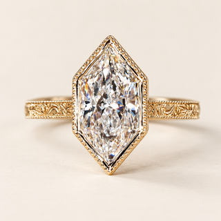 Dutch marquise cut lab grown diamond engagement ring with full geometric bezel, decorative milgrain edging and engraved vintage yellow gold shoulders.