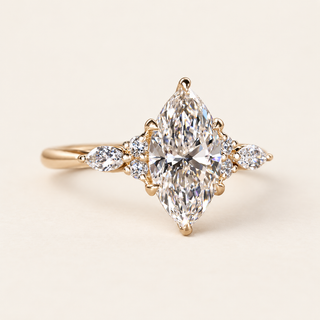 Marquise cut lab grown diamond cluster engagement ring with pointed center, pear-shaped marquise side diamonds, round accents and polished yellow gold band.