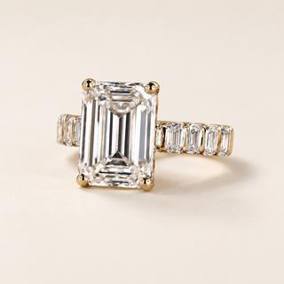 Emerald cut lab grown diamond engagement ring with a 5.00 ct center, four-prong setting and emerald cut diamond shoulders in polished yellow gold.