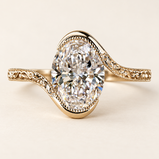 Oval cut lab grown diamond engagement ring with asymmetrical polished gold bypass setting, milgrain-bordered scroll shoulders and 2 ct oval center in yellow gold.