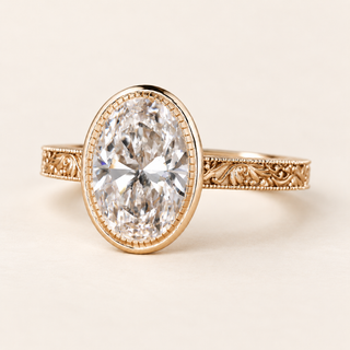Oval cut lab grown diamond engagement ring with a full milgrain-detailed bezel, ornate filigree shoulders and polished yellow gold band.
