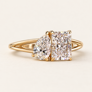 Radiant and pear cut lab grown diamond Toi et Moi engagement ring with asymmetrical prong baskets and polished yellow gold split shank.
