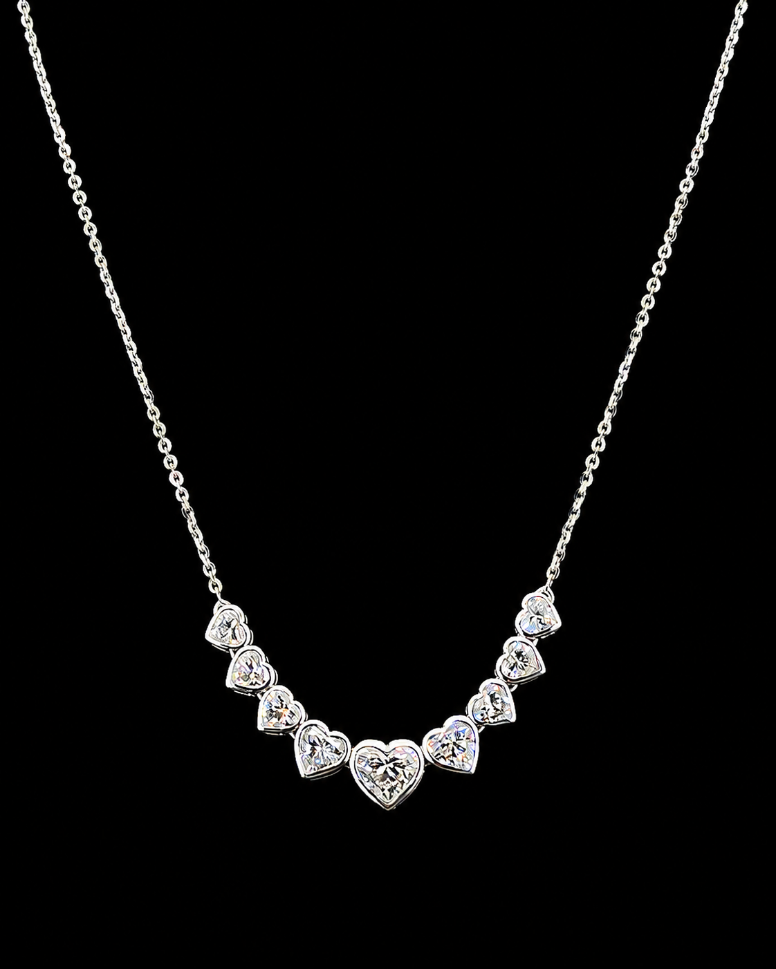 Main: White gold pendant with nine graduated heart lab grown diamonds on black
Detail: Close-up of nine heart lab grown diamonds arranged in a graduated curved pendant
Side: White gold heart diamond pendant showing individually set graduated lab grown diamonds