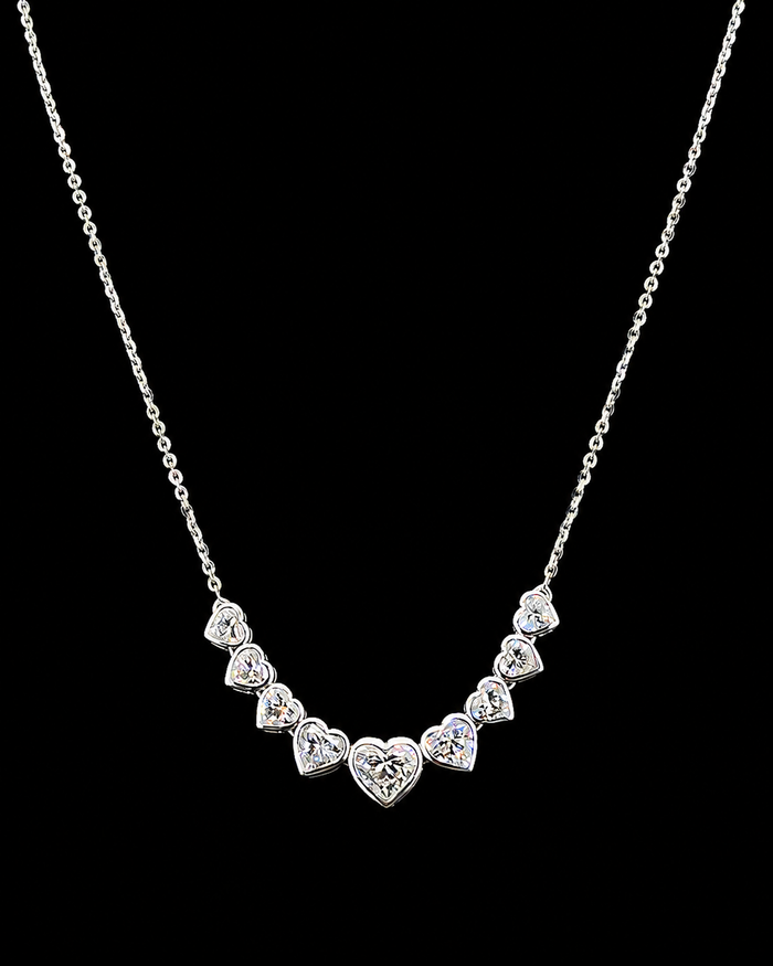 Main: White gold pendant with nine graduated heart lab grown diamonds on black
Detail: Close-up of nine heart lab grown diamonds arranged in a graduated curved pendant
Side: White gold heart diamond pendant showing individually set graduated lab grown diamonds