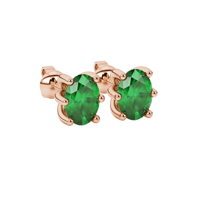 Close-up, oval cut emerald green gemstone earrings, rose gold six prong setting.