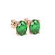 Close-up, oval cut emerald green gemstone earrings, rose gold pavé basket.