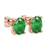Close-up, oval cut emerald green gemstone earrings, rose gold surprise diamond setting.