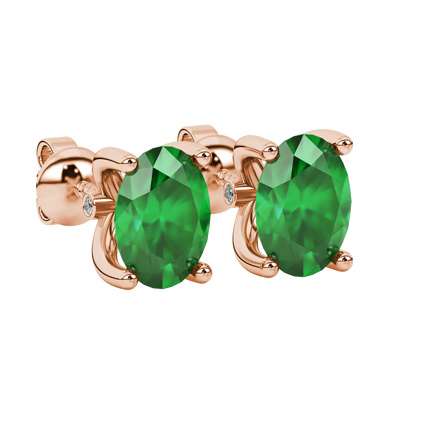 Close-up, oval cut emerald green gemstone earrings, rose gold surprise diamond setting.