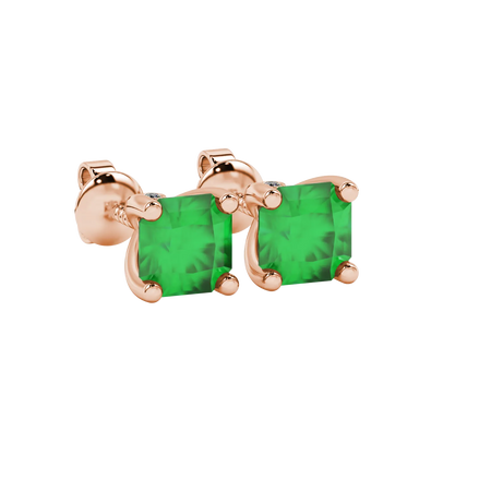 close-up shot of radiant-cut emerald green gemstone stud earrings with a rose gold surprise diamond accent.